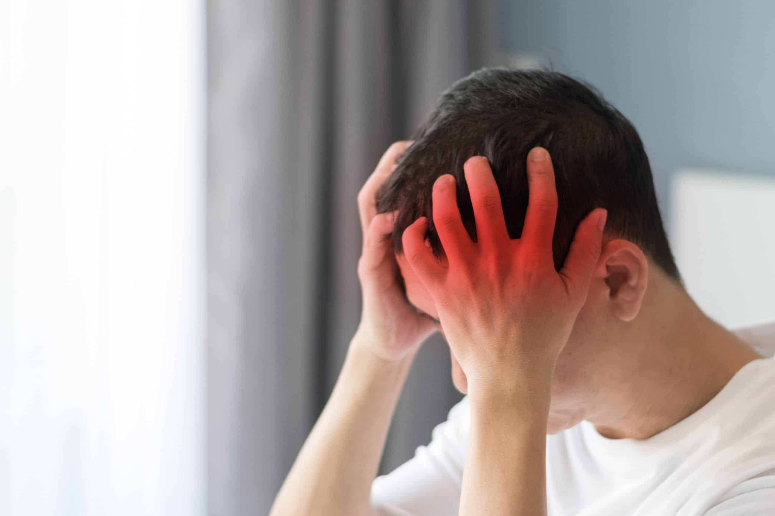 A man grasps his head while he deals with dizziness.