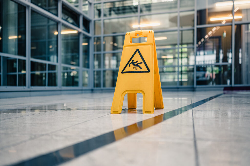 A caution sign indicating a wet floor in the hallway of a building.
