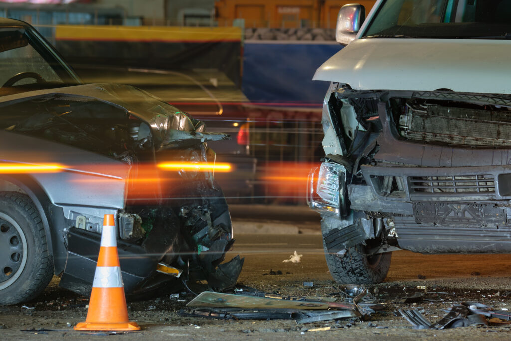 Damaged in heavy car accident vehicles after drunk driving collision on city street crash site at night. 