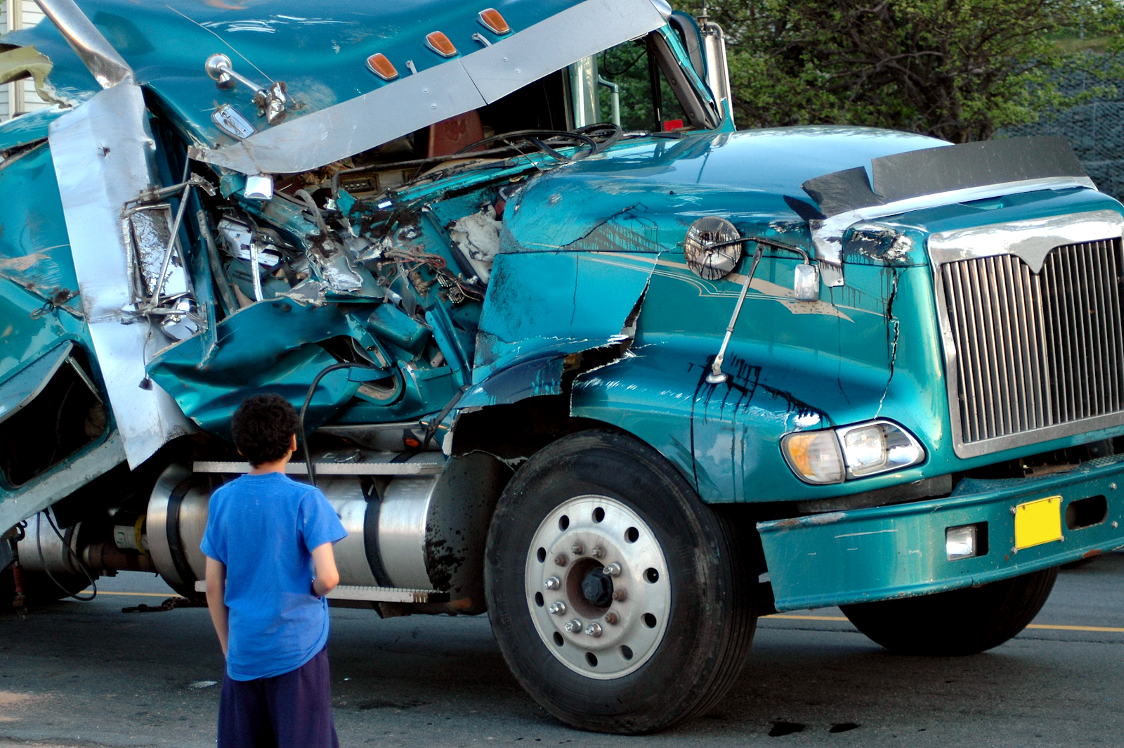 truck accident in fairfax, man looking at the passenger side of a damaged blue semi truck