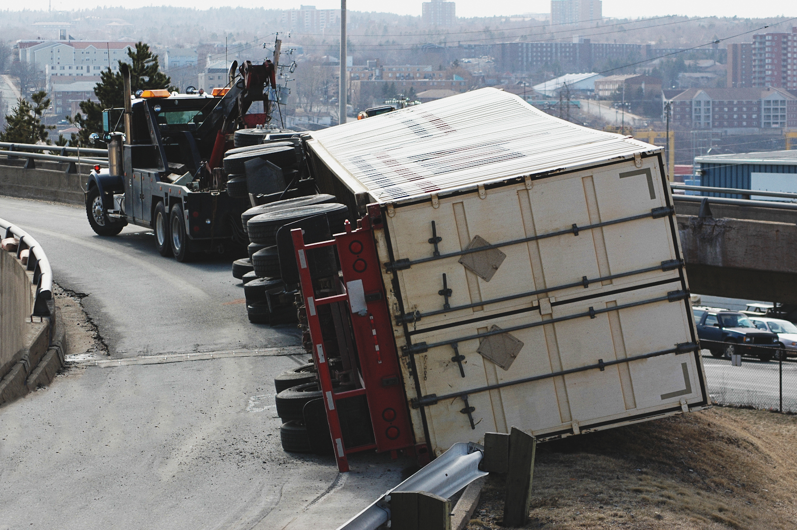 truck rollover accident on a highway involving passenger vehicles, tow truck backing up to help the flipped truck