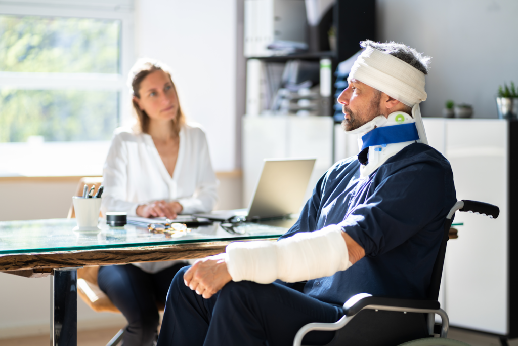 man in bandages and wheelchair talking to a personal injury lawyer