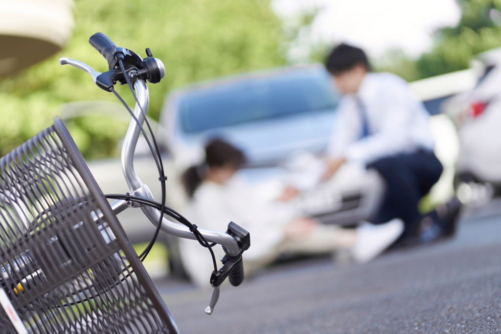 bicycle in the foreground and blurred image of two people on the ground, man helping woman after hitting her with a car