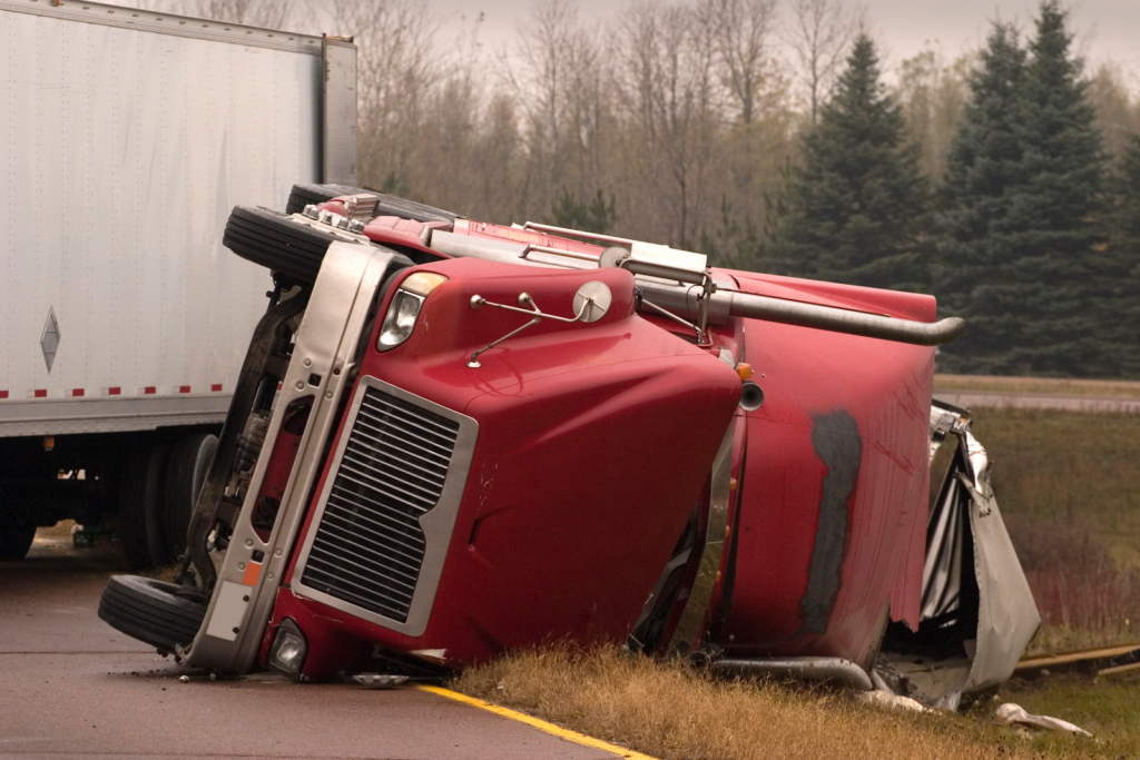 red truck tipped over on a highway on a fall day