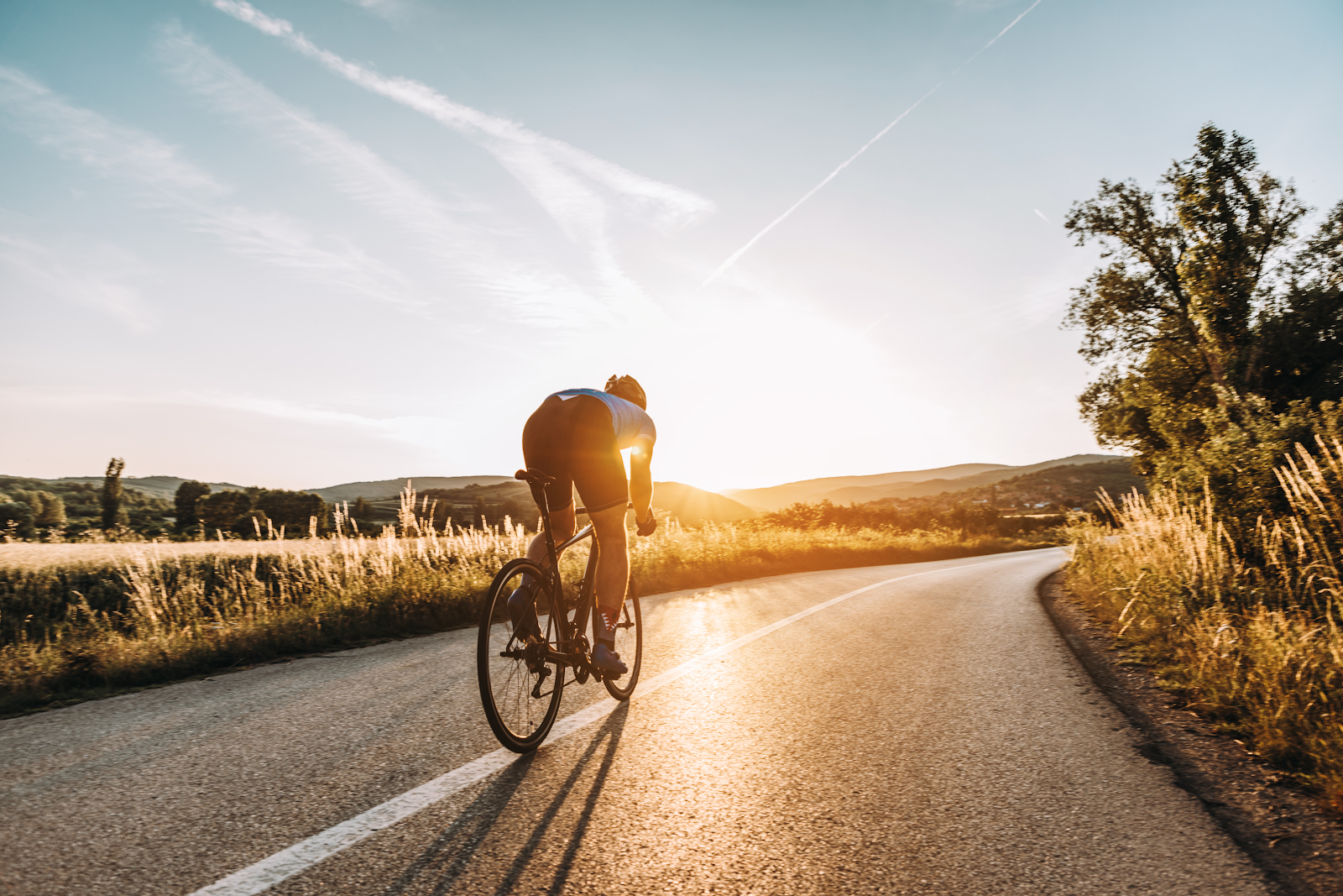 bicyclist riding at sunset down the path