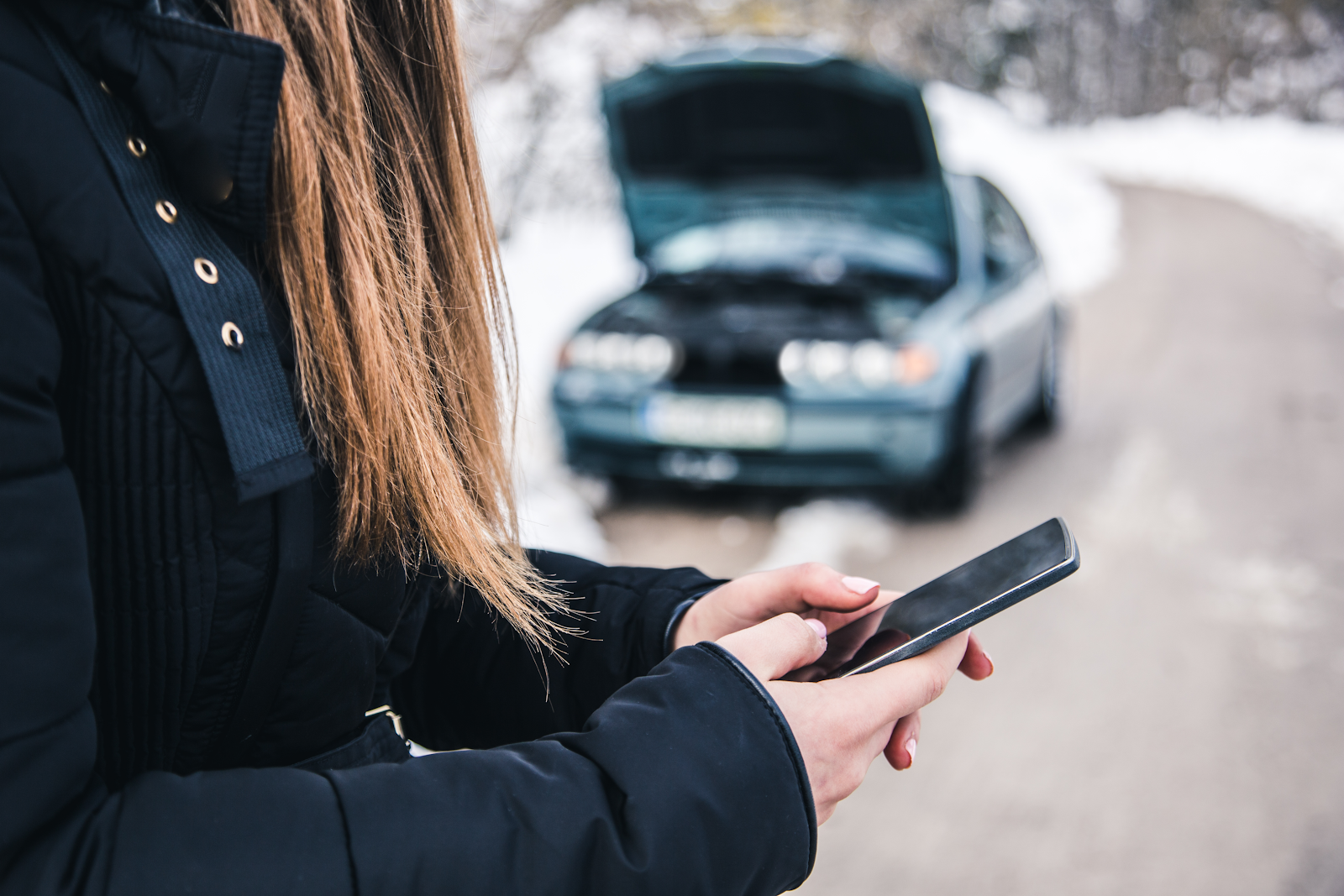 woman outside of her car after an accident on her phone filing an insurance claim