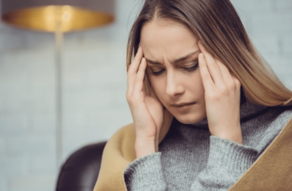 a woman holds her temples and closes her eyes coping with her dizziness after a car accident.