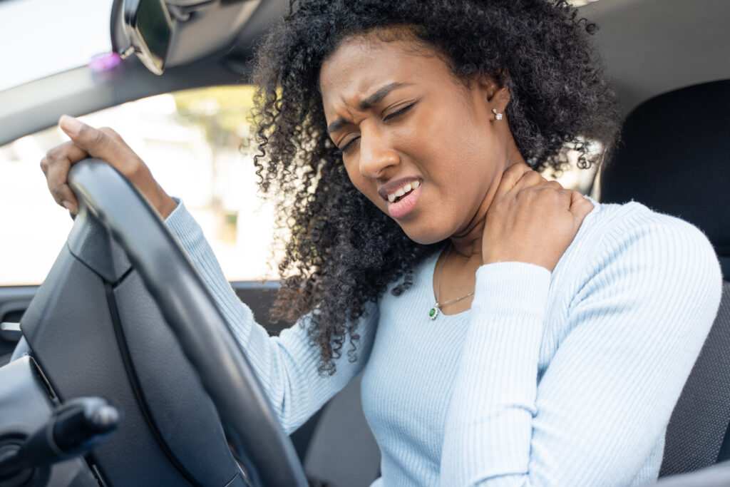 a woman winces in pain after a car accident.