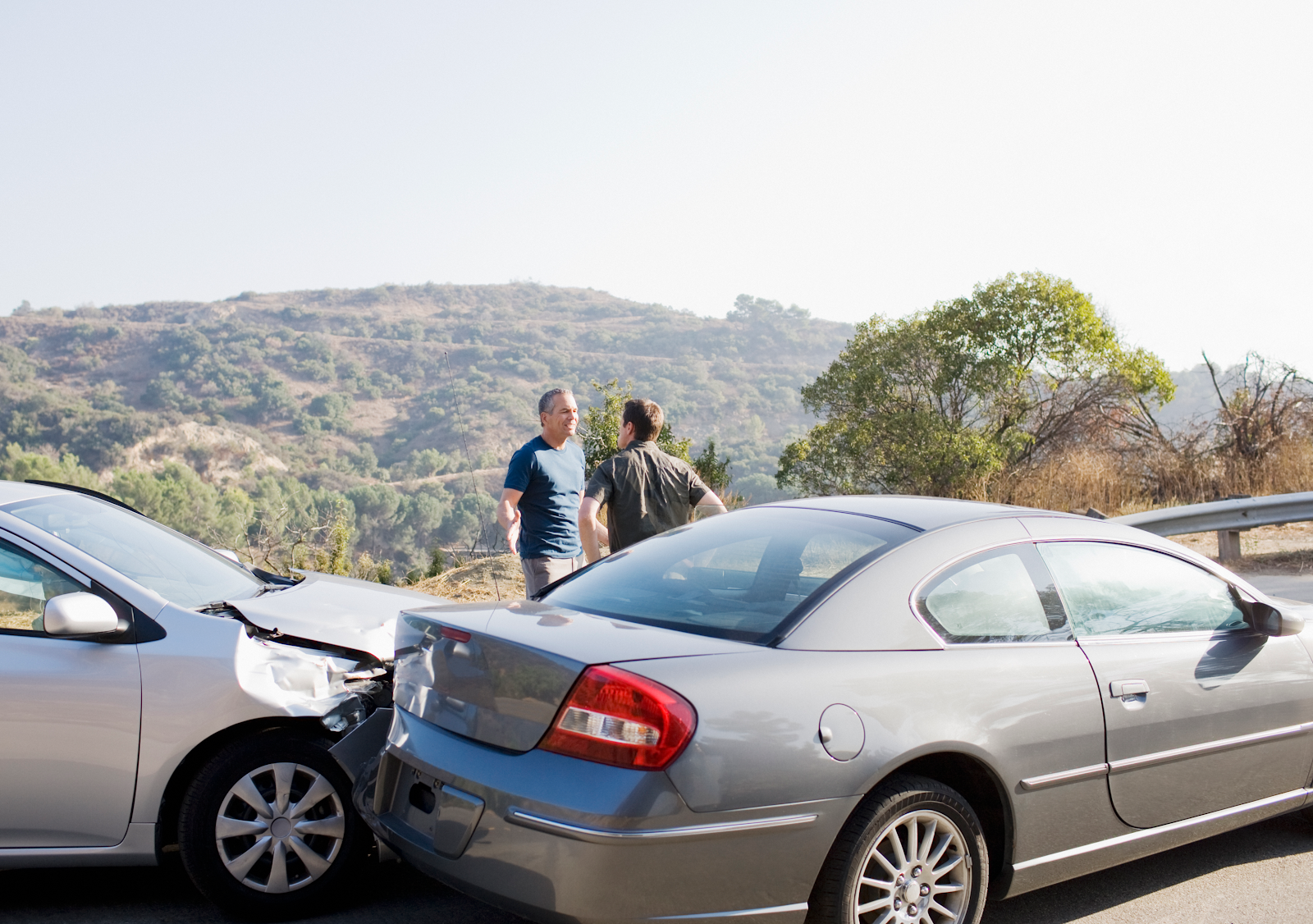 two men looking at their damaged cars after a car accident.