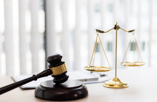 a gavel sits in front of the scales of justice.