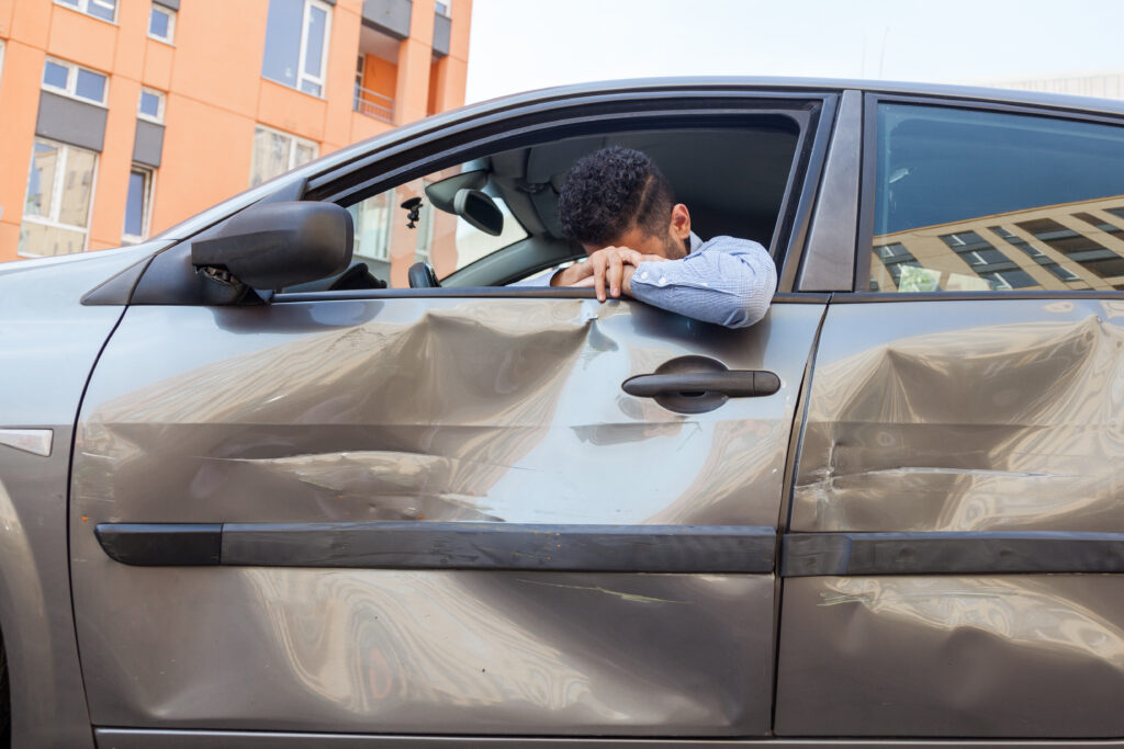 A man leans out of the driver's side window of his car after he was involved in a side-impact car accident.