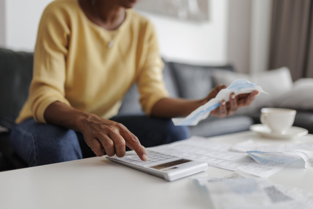 A woman uses a calculator to tally her expenses to present to the insurance adjuster.