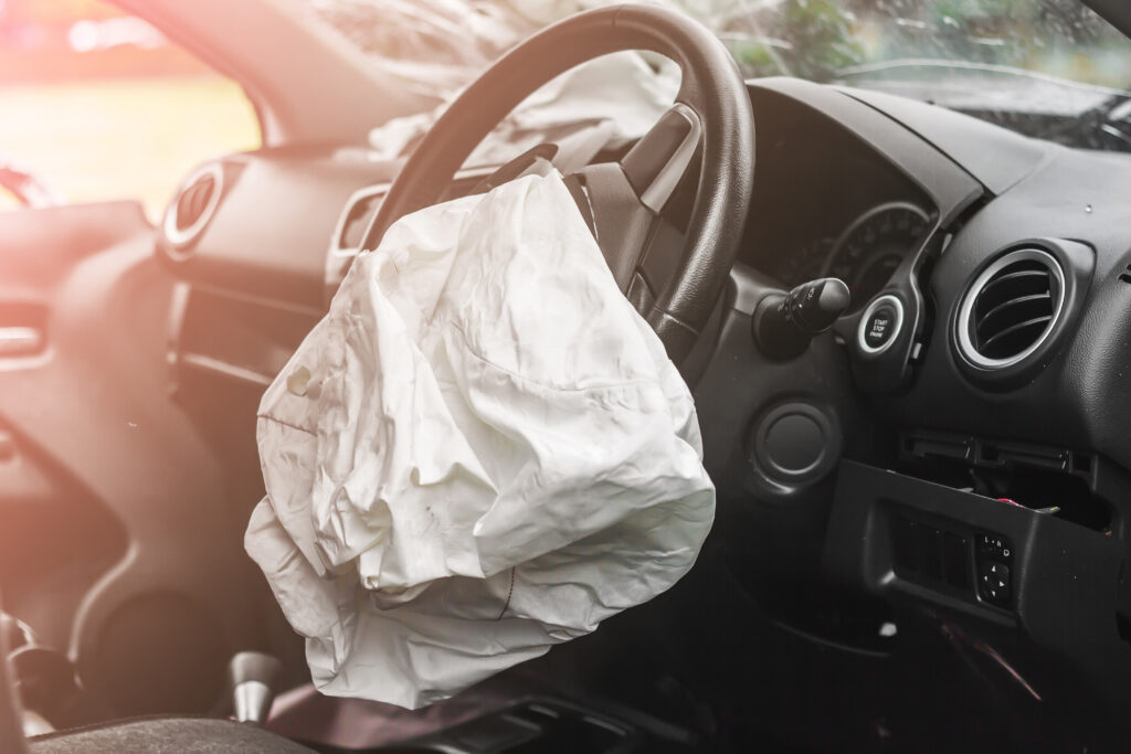 An interior view of a car that has just been in an accident. The steering wheel airbag has been deployed.