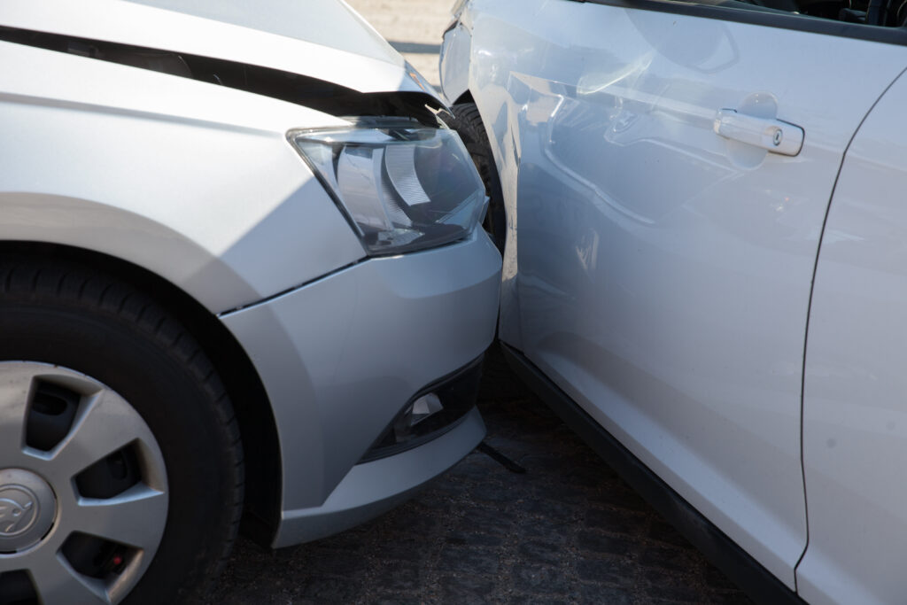 A close-up view of a side-impact collision between two white cars. 