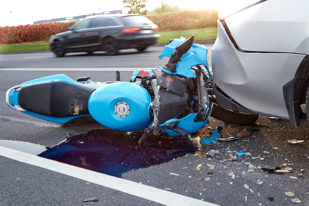 a bright blue motorcycle is heavily damaged after a collision with a car.